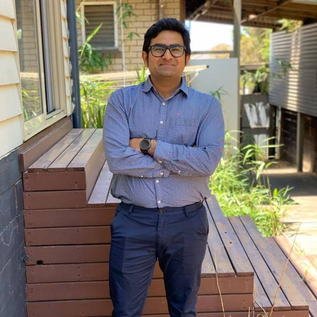 Standing with arms crossed on a wooden deck